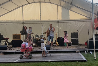 Musiker mit Kindern auf der Bühne, einige Kinder tanzen und spielen vor der Bühne