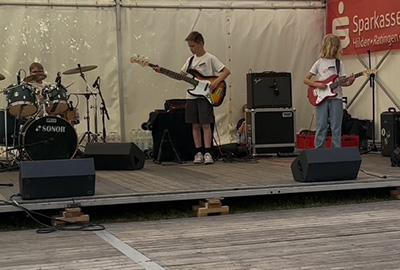 Junge Band mit Schlagzeug, Bass und Gitarre spielt auf der Open-Stage-Bühne