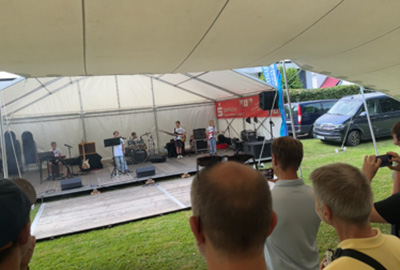 Publikum beobachtet eine Band, die unter einem weißen Zelt auftritt