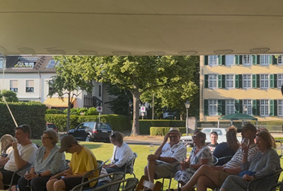 Zuschauer sitzen in Reihen auf Stühlen im Freien vor der Bühne